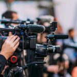 Liberty Island Horror: Arrest Follows Night Capsize Video cameras on tripods at a media event