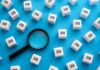 TODAY: Jobs Sputter Again — What’s Breaking? Magnifying glass among cubes labeled job on blue background