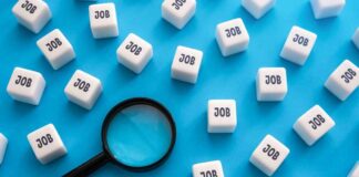 Magnifying glass among cubes labeled job on blue background