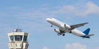 An airplane taking off near an airport control tower