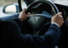 Tesla’s $50K Gambit Starts Now Person driving a Tesla car steering wheel