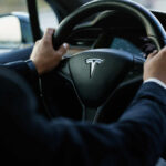 Person driving a Tesla car steering wheel