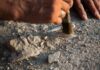 Archaeologist brushing dust from a small artifact in the ground