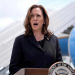 Kamala Harris speaking in front of airplane stairs.