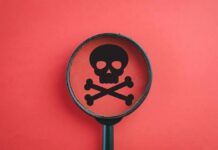 Famed Colosseum Goes Dark After Fatal Tragedy Magnifying glass focusing on a skull and crossbones symbol against a red background