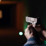 3 Down As Workplace Gunfire Erupts Hands aiming a pistol at an indoor shooting range