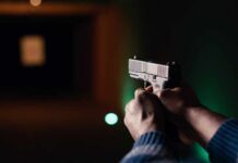 3 Down As Workplace Gunfire Erupts Hands aiming a pistol at an indoor shooting range