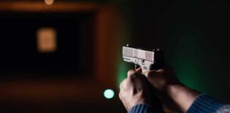 Hands aiming a pistol at an indoor shooting range