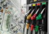 Fuel pump nozzles next to spread of U.S. hundred-dollar bills