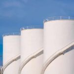 Large white industrial storage tanks with exterior spiral staircases