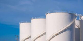 Large white industrial storage tanks with exterior spiral staircases