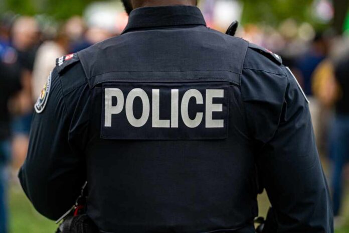 Back view of a police officer wearing a uniform with 'POLICE' displayed