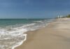 Sandy beach with gentle waves under a clear blue sky