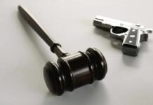 wooden judge's gavel with a handgun in the background