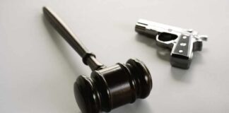 wooden judge's gavel with a handgun in the background