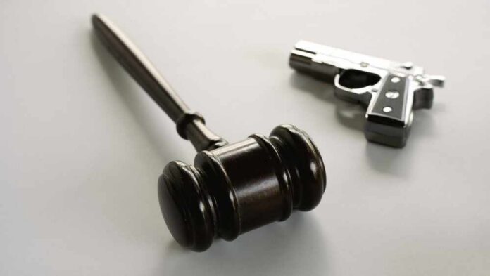 wooden judge's gavel with a handgun in the background