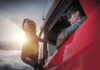 Truck driver looking out window at sunset.