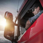Truck driver looking out window at sunset.