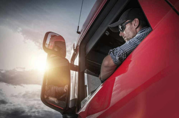 Truck driver looking out window at sunset.