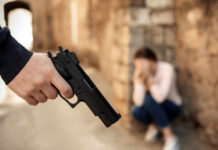 Jealousy Ping, One Shot, Chaos Hand holding a handgun with a distressed person in the background