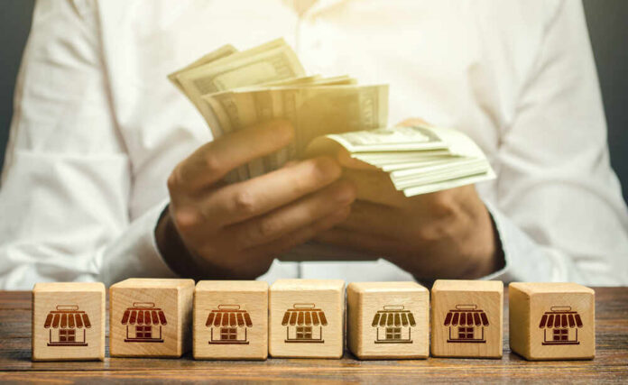 Blocks,Symbolizing,Business,Network,And,Businessman,Counting,Money.,High,Income Person counting cash with wooden blocks depicting store icons
