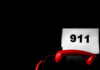 911: Neglectful Mom Arrested A red telephone next to a sign displaying the number 911 on a dark background