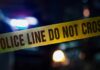 Police tape with blurred emergency lights in the background
