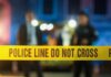 Horror: Cops’ Home Turns Deadly Police tape at a night scene with blurred officers in the background