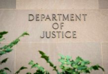 Illegal Firing Triggers DOJ Meltdown Sign displaying 'Department of Justice' on a stone wall