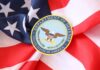 DOD’s Livestream Promise Sparks Fury Soldiers in uniform facing American flag outdoors.