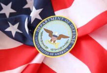 DOD’s Livestream Promise Sparks Fury Soldiers in uniform facing American flag outdoors.