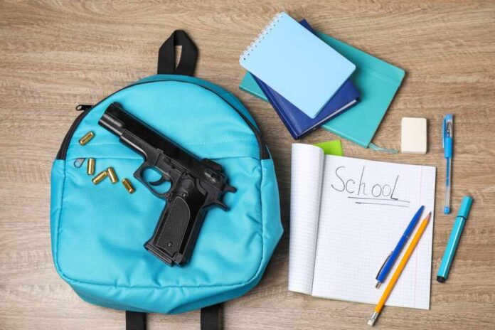 Gun,,Bullets,And,School,Stationery,On,Wooden,Table,,Flat,Lay A blue backpack with a handgun and school supplies on a wooden surface