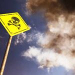 Death Rocks Tribute Yellow skull and crossbones warning sign against smoky sky