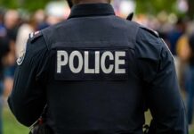 Back view of a police officer wearing a uniform with 'POLICE' displayed