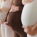 Pregnant women standing side by side holding their bellies