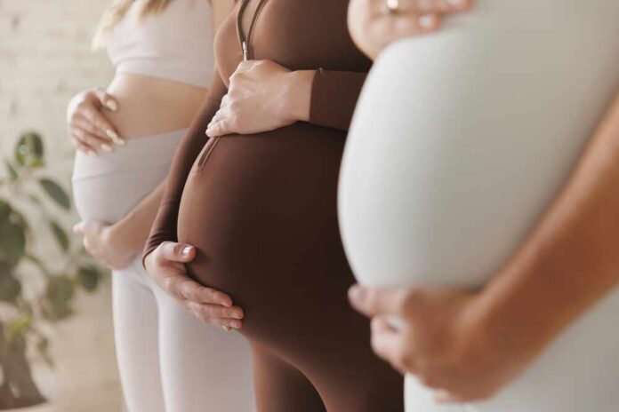 Pregnant women standing side by side holding their bellies