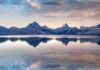 Alps Meltdown: Two Years, Vanished Ice Snow-capped mountains reflected in a calm lake at sunrise