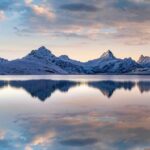 Snow-capped mountains reflected in a calm lake at sunrise