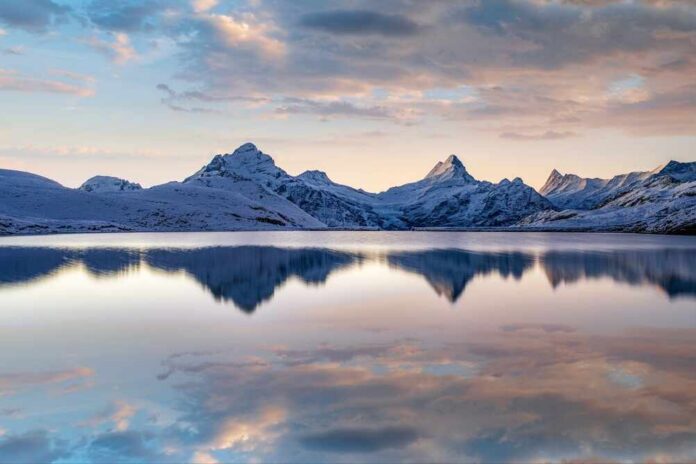 Lake,Bachalpsee,,Switzerland,With,Jungfrau,,Eiger,,Monch,And,Other,Peaks Snow-capped mountains reflected in a calm lake at sunrise