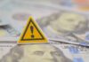 $1M Heist Impacts Americans A warning sign placed on top of U.S. dollar bills