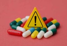 Warning sign among assorted capsules on pink background