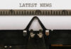 Lunch Lines Or Layoffs? Close-up of a typewriter with a sheet of paper displaying the words 'LATEST NEWS'