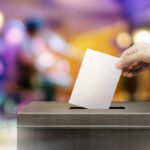 Hand placing ballot in voting box.