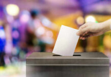 ELECTION CRIME: DOJ Targets State Hand placing ballot in voting box.