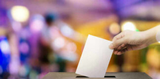 Hand placing ballot in voting box.